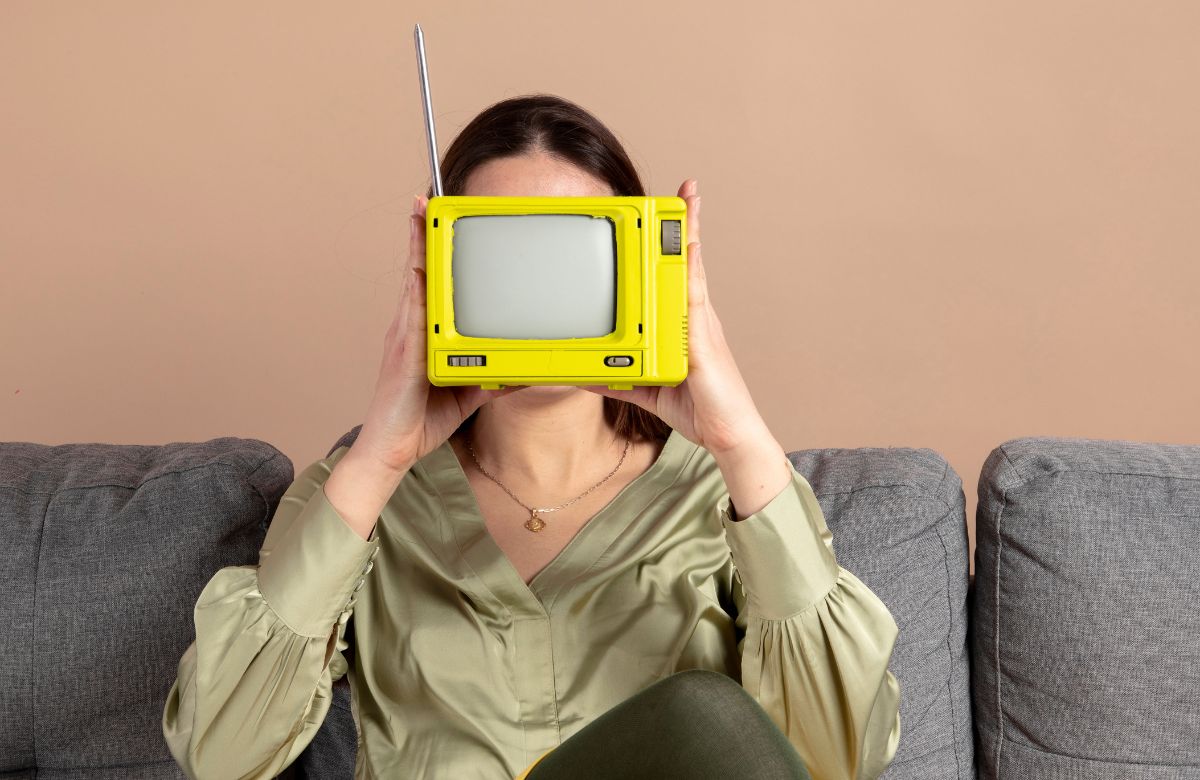 Imagen de una mujer sentada en un sofá sujetando una tv pequeña